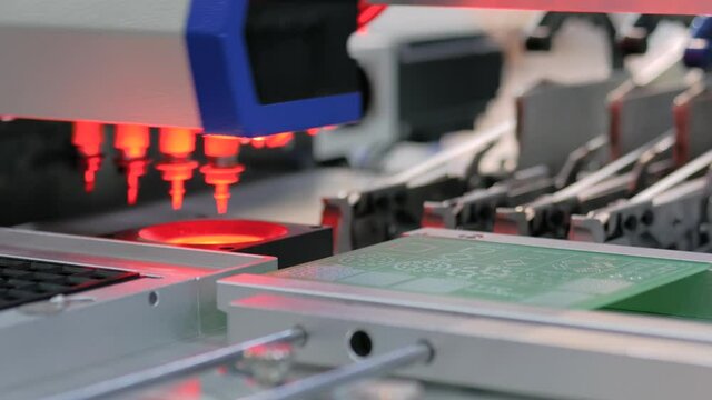 Automatic SMD pick and place machine during work - assembly of computer printed circuit board at factory. Automated technology, industrial, robotic, electronic, production, manufacturing concept