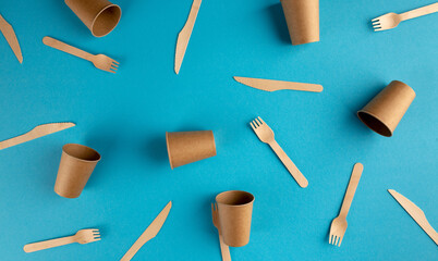 Wooden forks, knives and paper glasses pattern on blue background