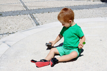 A three-year-old boy plays with a toy car outdoors on a sunny summer day. Kids toys. The child plays with toys.