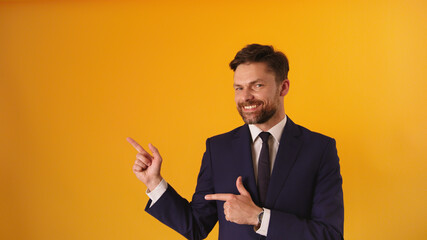 Portrait of cheerful satisfied handsome guy in formal outfit pointing fingers on empty space . High quality photo