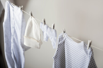 Laundry concept. Cleanliness, ironing, washing of children's clothes. Baby things dry on a rope close-up and copy space on a gray wall background.
