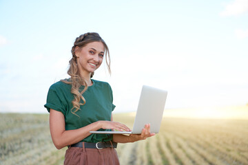 Woman farmer smart farming standing farmland smiling using laptop Female agronomist specialist...