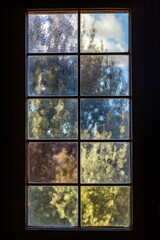 A window with multi-colored glass that overlooks a park or garden