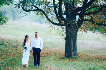 Fototapeta premium Beautiful caucasian couple walking in the autumn park. Honeymoon. Place for text