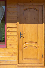Naklejka na ściany i meble wooden yellow door with black handle lightened by sun. Entrance into country house.