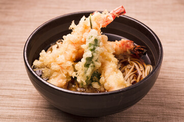 buckwheat soba noodle soup with shrimp tempura in a ceramic bowl