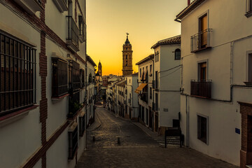 A view down the street of Antequera, Spain leading up to towards the Moorish Alcazaba palace fortress at sunset on a summers evening