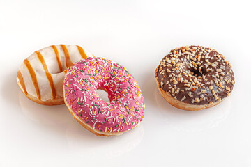 freshly baked chocolate, caramel and strawberry donuts on a  white glass surface