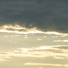 Cloudy mood over Lake Garda in Italy. Dark clouds against the bright sky. A bird flies lonely across the sky. Scraps of cloud spread out. Evening mood.