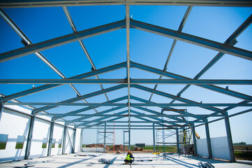 Steel frame workshop is under construction against a blue sky