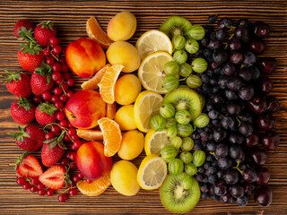 Fresh berries and fruit on a wooden background. Rainbow color. the concept of healthy eating. The view from the top