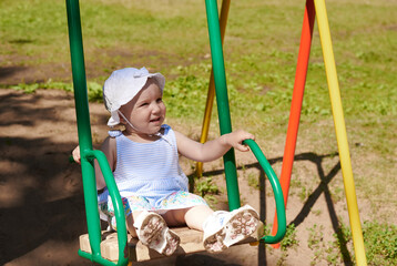 A baby rides on a swing. A baby have a fun on a flip-flap in the park