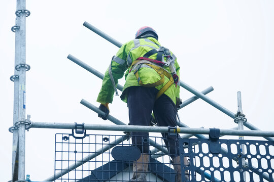 Scaffold worker dismantling access structure on construction building site