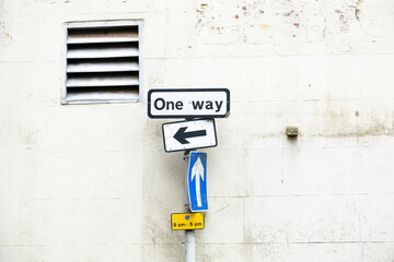 One way directional arrow sign against white wall background