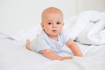 Cute baby boy smiling lies in the bed of the house. bedding for children