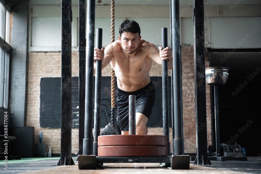 Wall mural fit male athlete doing exercises working out in the gym