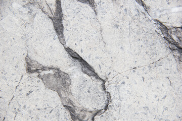 Light natural stone with cracks. Marble texture. Grey stone background.