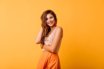 Shy european woman in yellow clothes posing in studio with sincere smile. Spectacular red-haired...