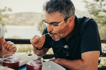 Adult man eating salad outdoors.