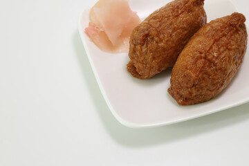 白い皿にのったいなり寿司とガリ