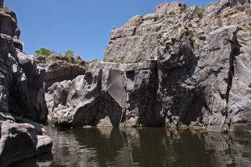 Adventure. Geology. View of the river flowing along the rocky cliffs and stone wall in Mina Clavero, Cordoba, Argentina.