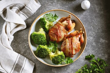 Baked quail in bacon with boiled broccoli and olive oil.