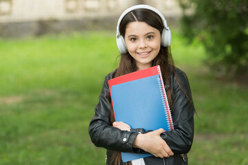 Fototapeta premium Girl listening audio carry textbooks on way to school, school club concept