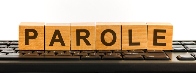 PAROLE word made with building blocks. A row of wooden cubes with a word written in black font is located on a black keyboard.