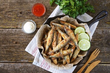 Grilled little fish in cornmeal and lime. On an old wooden background.