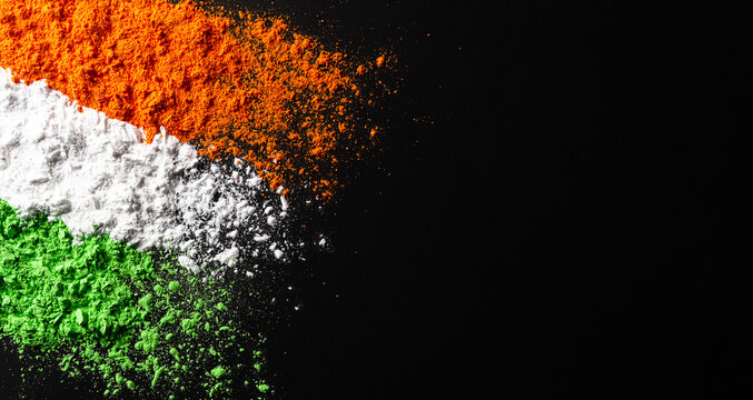 Indian Independence Day celebration background concept. Symbolic flag colors, red, green and orange powders colour splashed over dark background.