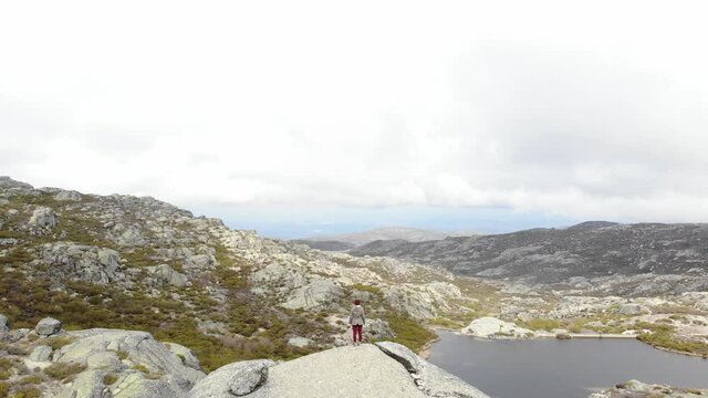 Aerial drone shot of woman standing on boulder enjoying the view of Covao dos Conchos, Serra da Estrela
