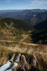 Carpathian mountain landscape with couple legs in hiking shoes in foreground