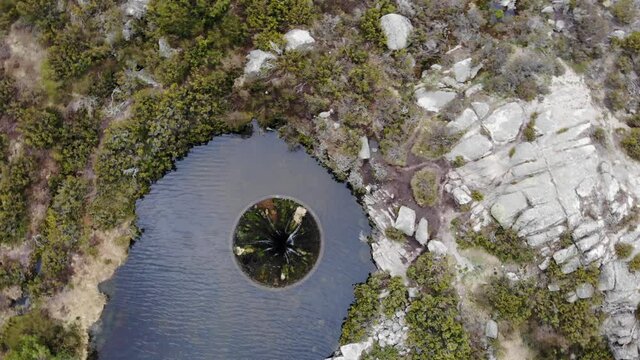 Aerial drone shot of big sinkhole constructed as water spillway at Covao dos Conchos dam lake in Serra da Estrela