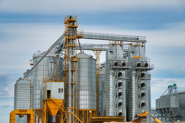 Fototapeta na wymiar Agribusiness concept. Metal silos for grain storage, drying, cleaning agricultural products, flour, cereals and grain on agro-processing and manufacturing plant.