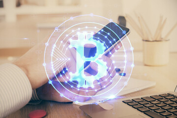 Double exposure of man's hands holding and using a phone and crypto currency blockchain theme...