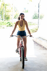 Naklejka premium Youthful female teenager showing confident smile while riding bicycle on a warm and sunny day in Southern California.