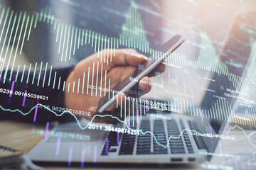 Double exposure of man's hands holding and using a phone and financial graph drawing. Analysis concept.