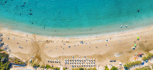 Aerial top view panorama of beautiful Coral beach in Paphos with azure seawater, Cyprus. Sand coast with umbrellas, sunbeds, people and clear sea water.