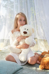 Little girl in white chiffon tent with toy