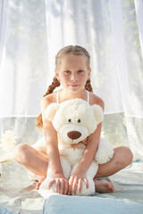 Little girl in white chiffon tent with toy