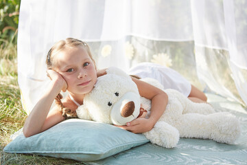 Little girl in white chiffon tent with toy