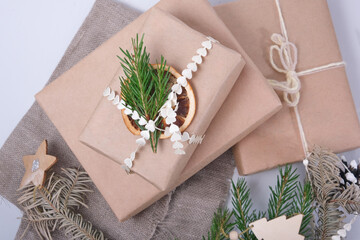 gift box wrapped in eco paper and decorated with dried orange fresh branch of a Christmas tree, natural spruce branches and pine cones for decorating gifts in eco style