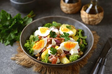 Salad with potatoes, bacon, olives, feta cheese, egg and lettuce.