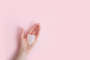 Female hand holds on the palm silicone menstrual cup. Reusable Intimate Hygiene. - obrazy, fototapety, plakaty