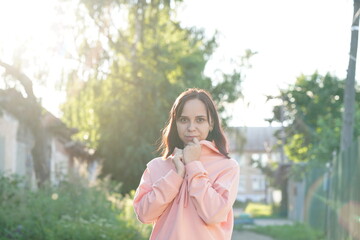Naklejka premium Portrait of young woman on street during sunset. Close up of pretty female looking at camera and smiling.