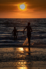 Fototapeta premium Kinder spielen im Sonnenuntergang im Meer