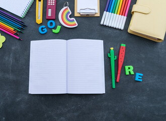 Stationery chalk board. Back to school. Open notepad on top of office supplies.