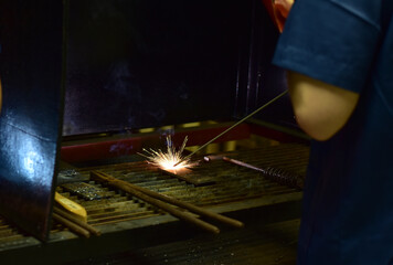 Thai Technologist Steel welding metal In the workshop class with flames and smoke floating out.