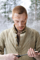 young man in a world war II military uniform with a combat cutlass in his hands in a snowy winter forest