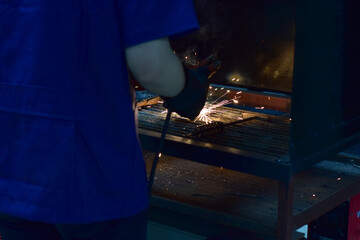 Thai Technologist Steel welding metal In the workshop class with flames and smoke floating out.